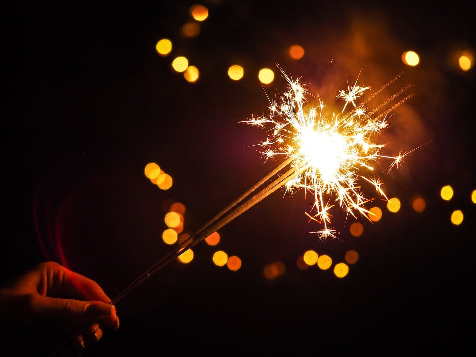 Iemand houdt een brandend sterretje (vorm van vuurwerk) vast