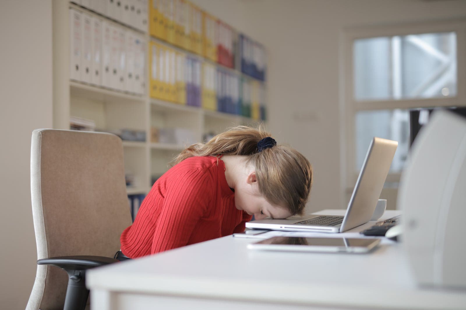 een vrouw die vermoeid is en met hoofd op laptop valt