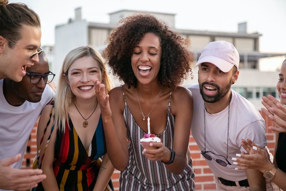 Gelukkige vrouw blaast kaars uit tijdens verjaardagsfeestje met diverse vrienden