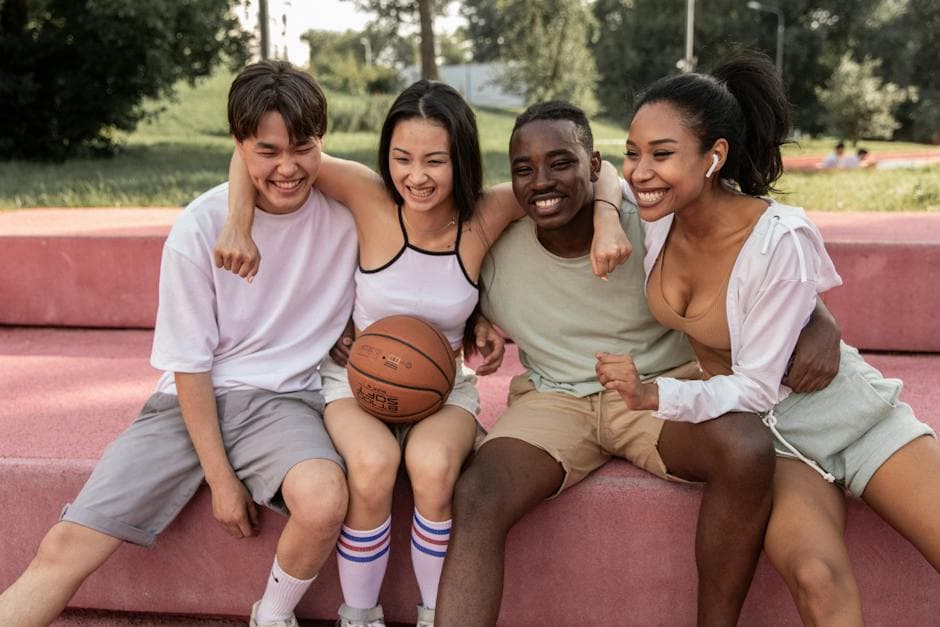 Vrolijke multiculturele vrienden omhelzen op de bank na basketbaltraining