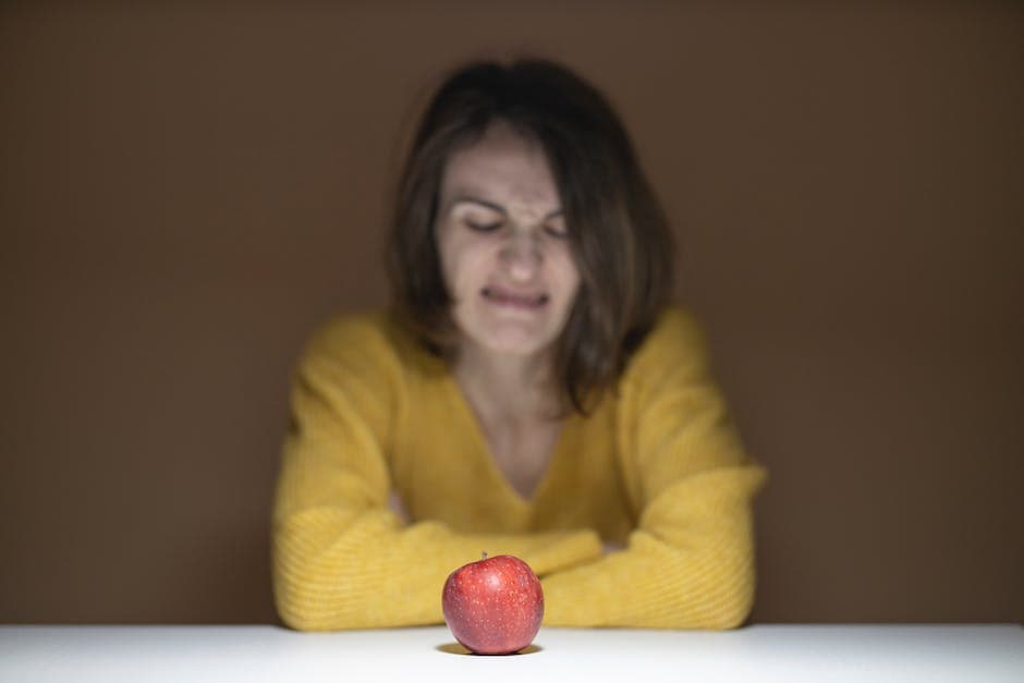 Vrouw kijkt vol afschuw naar de appel
