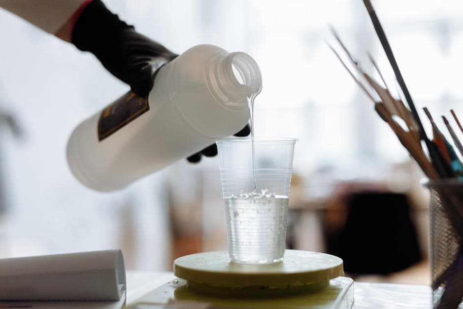 Persoon giet epoxyhars in een plastic bekertje.