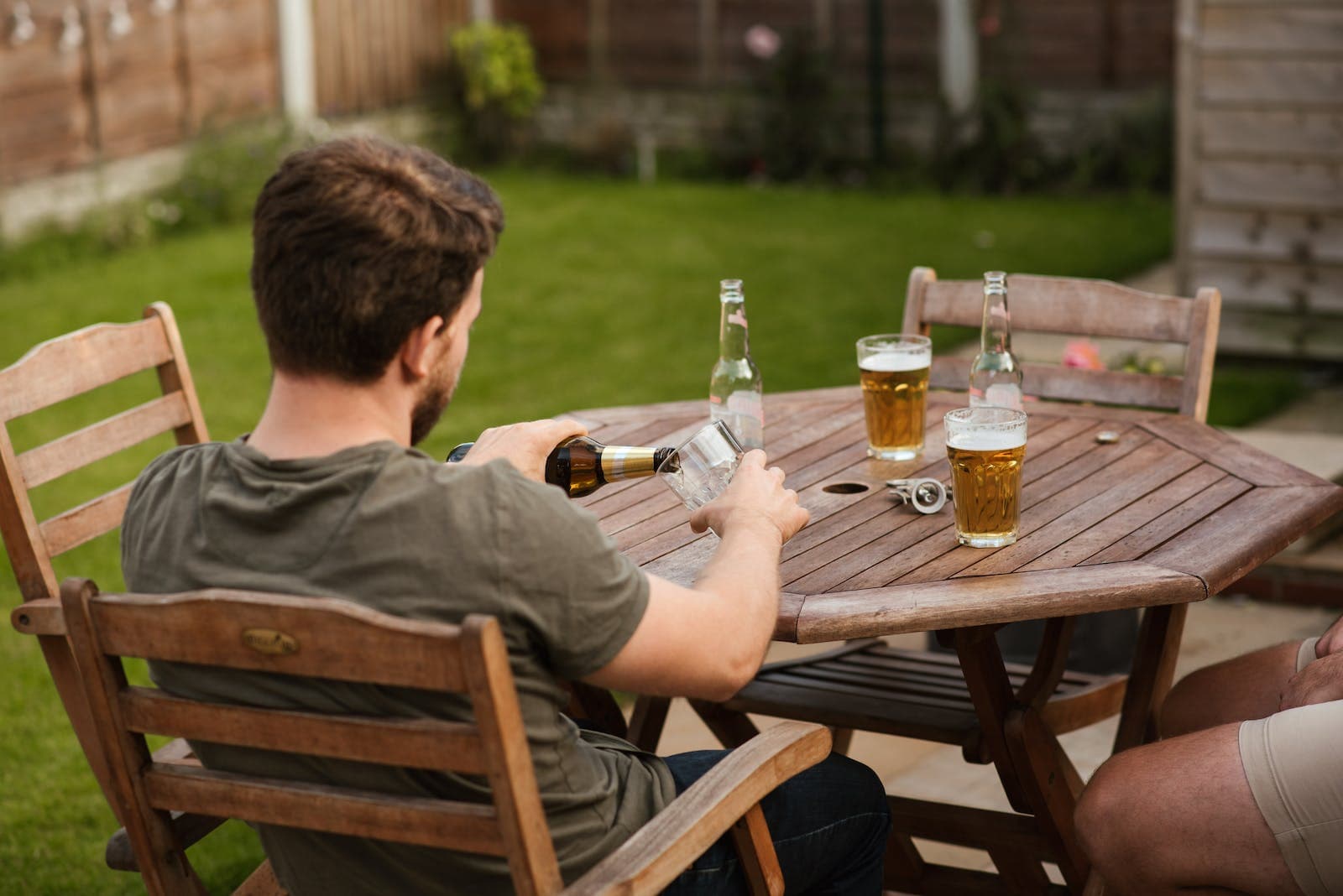 Man die een biertje inschenkt in zijn tuin