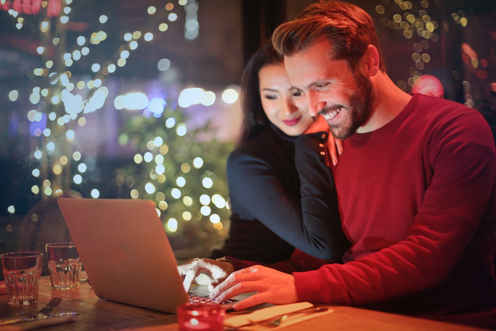 een koppel zit achter de computer in een kerstachtige verlichte omgeving