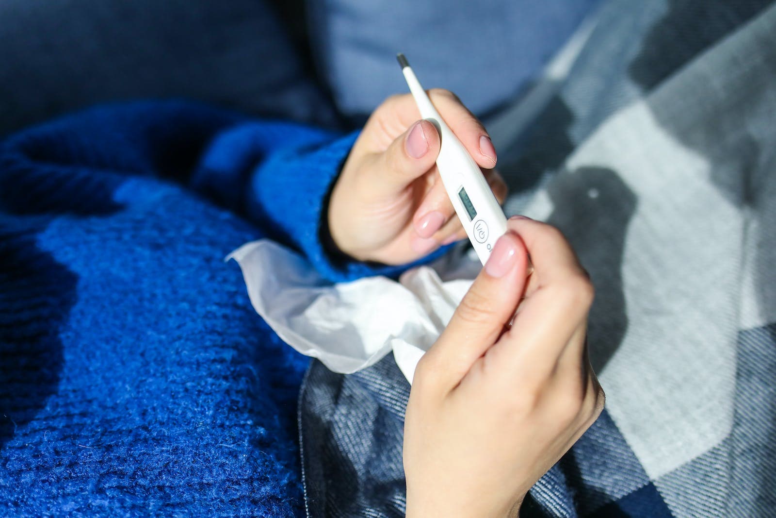 Iemand die op de thermometer controleert of diegene koorts heeft