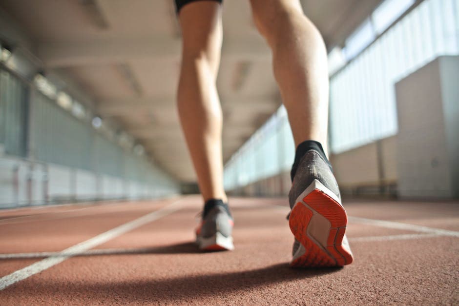 Fit uitziende hardloper staat op een renbaan in een atletiekarena