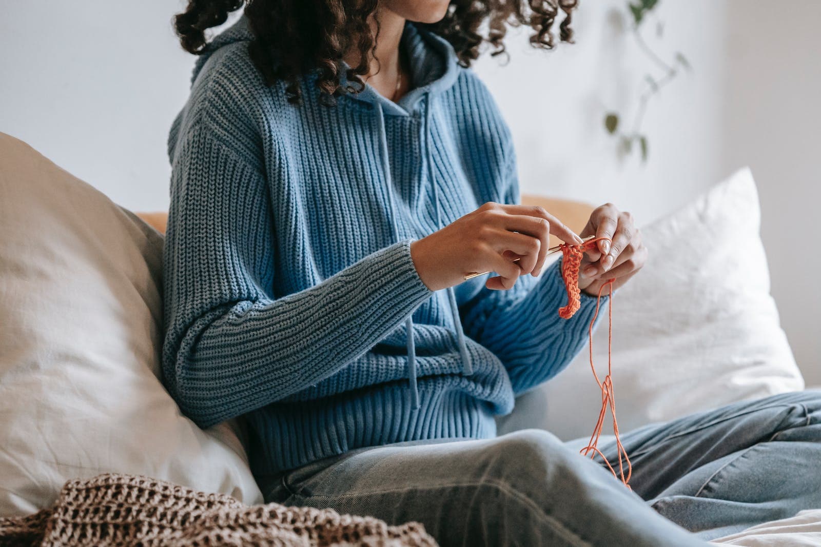 Woman sitting on sofa and doing needlework