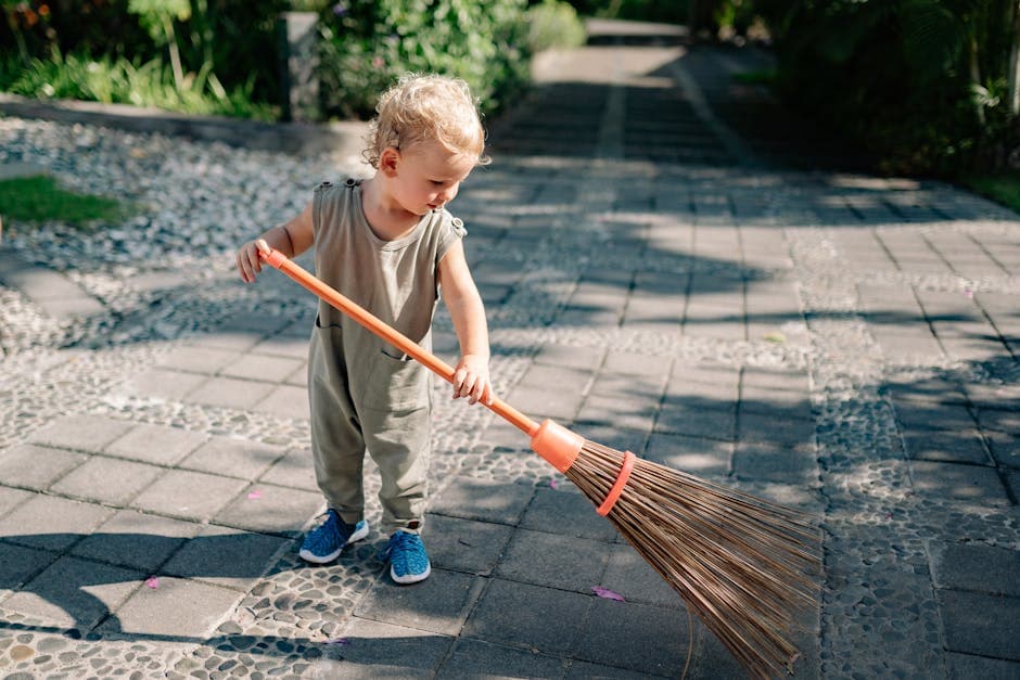 Kind veegt betonstraat met bezem